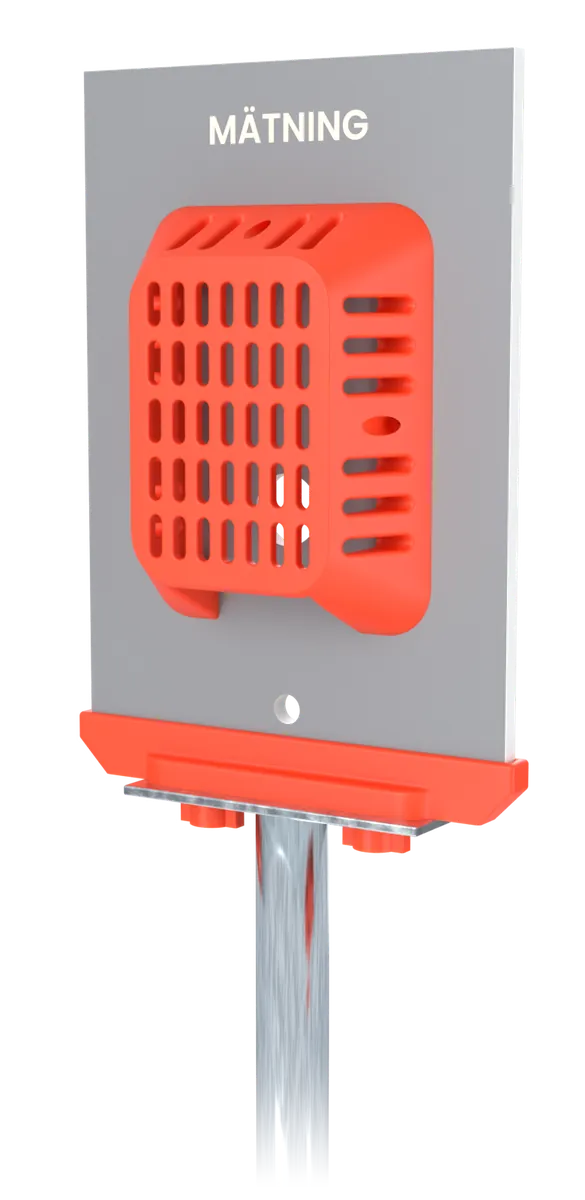 Sensorstativets övre del: en plywoodskiva med texten MÄTNING, ett orange skyddsgaller som är fäst med magneter samt ett orange fäste och ett åtdragningsvred på stolpen.